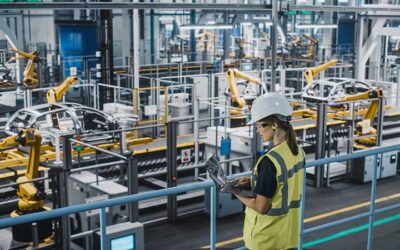 Female Car Factory Engineer in High Visibility Vest Using Laptop Computer. Automotive Industrial Manufacturing Facility Working on Vehicle Production with Robotic Technology. Automated Assembly Plant.